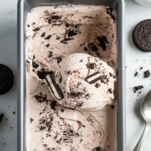 Close-up top-down view of creamy no-churn Oreo ice cream in a loaf pan with visible cookie chunks and natural lighting.