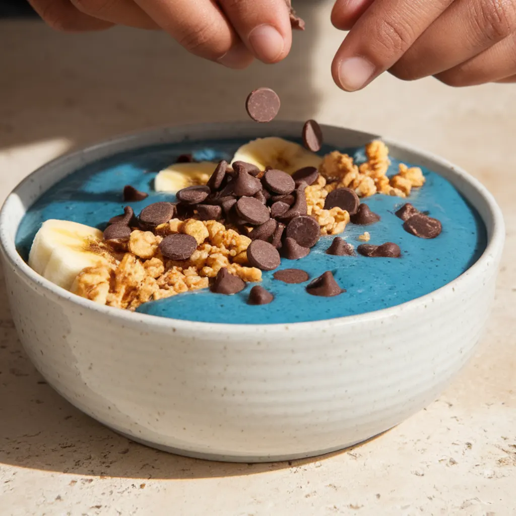 Adding chocolate chips to Cookie Monster smoothie bowl